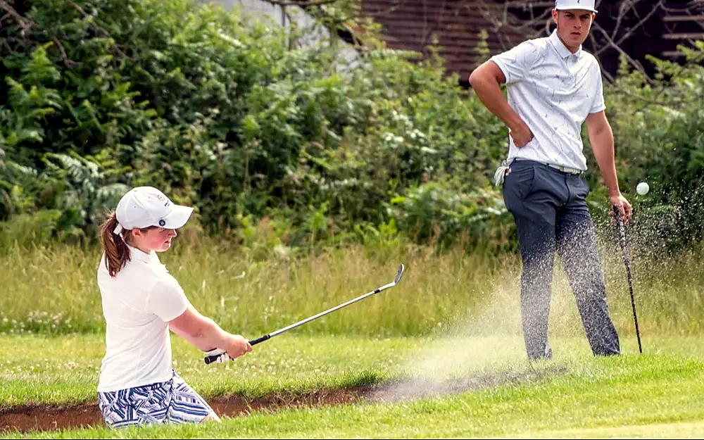 Junior golfers playing from a bunker