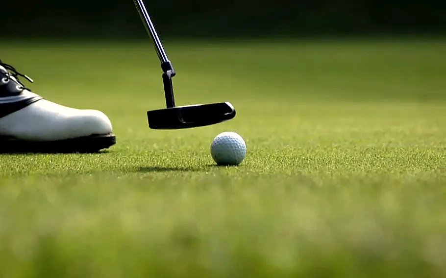 A putter about to strike a ball on the practice green