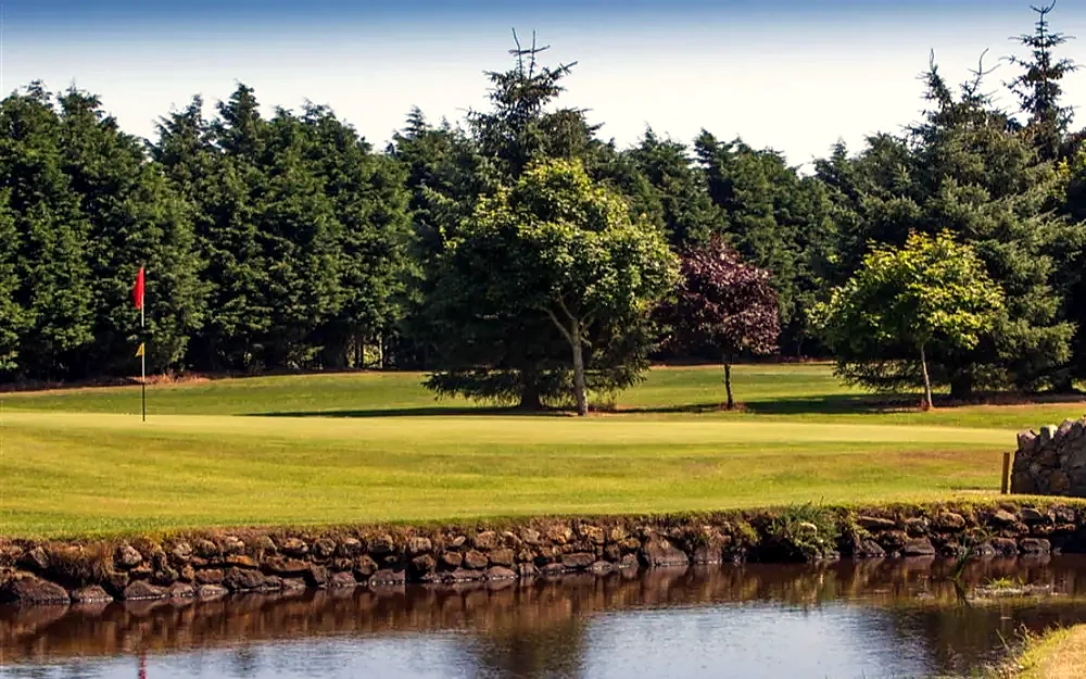 Water and mature trees beside a fairway